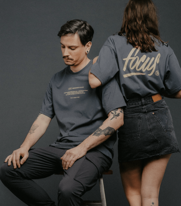 male model sitting and female model resting on him both wearing grey t-shirts